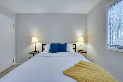 a white bedroom with a large bed with blue pillows at Dreamy Lake House - Fireplace, Firepit & Pet Friendly in Pocono Lake