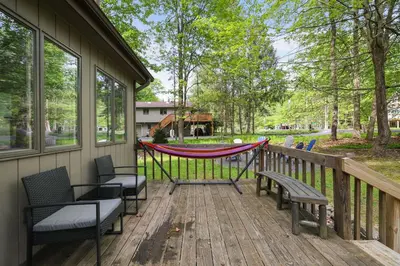 a porch with chairs and a hammock on a deck at Dreamy Lake House - Fireplace, Firepit & Pet Friendly in Pocono Lake