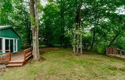 a house with a wooden deck in the woods at Charming, Pet-friendly Lake front Retreat WiFi in Ferndale