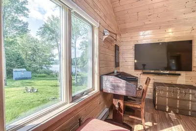 a living room with a tv and a large window at In the clouds your cozy- lake house in Swan Lake