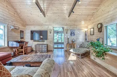 a living room with wood paneled walls and a tv at In the clouds your cozy- lake house in Swan Lake