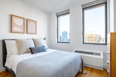 a white bedroom with a large bed and two windows at Hells Kitchen 1BR w Doorman nr Central Park NYC-521 in New York
