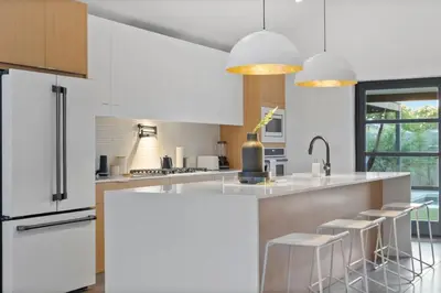 a kitchen with white cabinets and bar stools at Modern Home w Heated Pool in Philadelphia