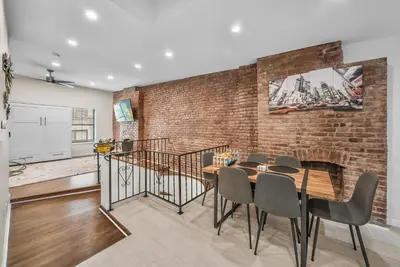 a dining room with a brick wall and a table and chairs at Free Parking -2BR,2Bath, 4Beds, Sleeps 6, 10 Min to NYC, 10 Min to Path in Hoboken