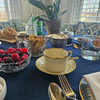 a table with a blue table cloth with a bowl of fruit at Peach Grove House in Warwick
