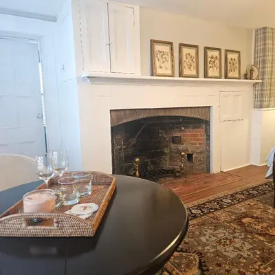 a living room with a table and a fireplace at Peach Grove House in Warwick