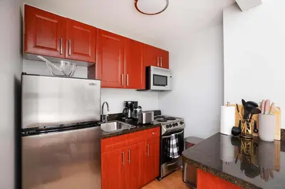 a kitchen with wooden cabinets and a stainless steel refrigerator at 73-812 New Studio UWS Doorman Gym in New York