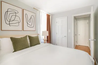 a white bedroom with a large white bed with green pillows at 73-806 New 1BR 1Bth UWS Doorman Gym in New York