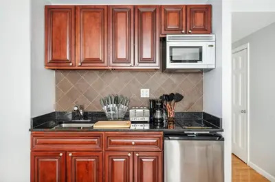 a kitchen with wooden cabinets and stainless steel appliances at 73-806 New 1BR 1Bth UWS Doorman Gym in New York