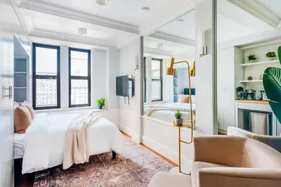 a white bedroom with a bed and a chair at 73-1509 New Studio UWS Doorman Gym in New York