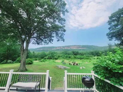 a porch with a bench and a grill and a field at The Yuzu stunning mountain retreat with hot tub in Gardiner