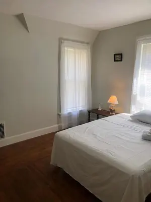 a bedroom with a white bed and two windows at Home Support And Care LLC in Binghamton