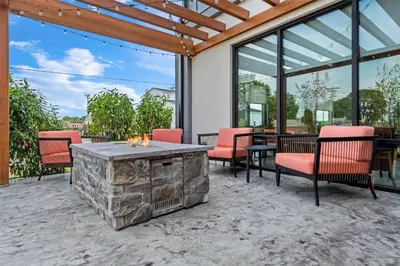 a patio with red chairs and a stone fireplace at Hampton Inn & Suites Intercourse, Pa in Intercourse