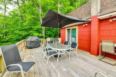 a wooden deck with a table and chairs and an umbrella at Mtn-View Deck and Grill Creekside Catskills Cabin! in Equinunk