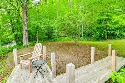 a wooden deck with a chair and a table at Mtn-View Deck and Grill Creekside Catskills Cabin! in Equinunk