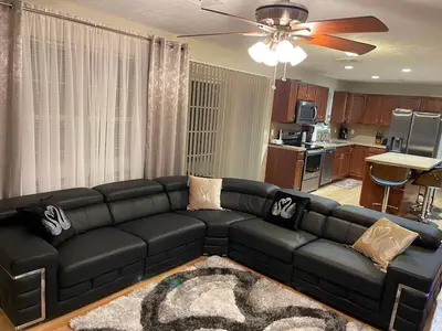 a black leather couch in a living room with a kitchen at Gorgeous house private pool hot tub playroom in Long Pond