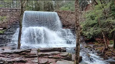 a waterfall in the middle of a stone wall at Gorgeous house private pool hot tub playroom in Long Pond