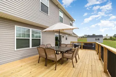 a wooden deck with a table with chairs and an umbrella at 10 Acre Hidden Gem in Dillsburg