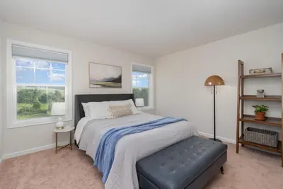 a bedroom with a bed with a ottoman and two windows at 10 Acre Hidden Gem in Dillsburg