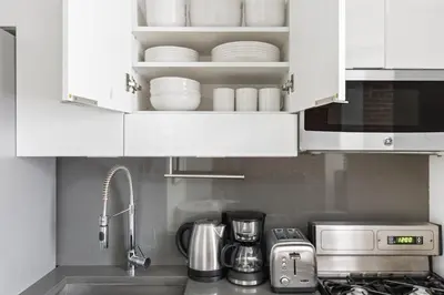 a kitchen with white cabinets and a sink with dishes at Blueground Nolita wd ac nr Little Italy NYC-1570 in New York