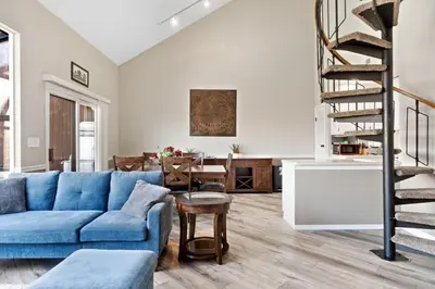 a living room with a blue couch and a staircase at Mountain Creek Townhouse in Vernon Township