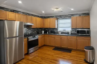 a kitchen with wooden cabinets and a stainless steel refrigerator at Tremont Hidden Treasure in East Orange