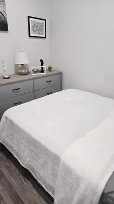 a white bedroom with a bed and a dresser at Serenity Haven in Irvington