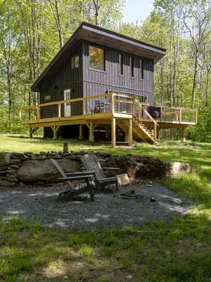 a cabin in the woods with a deck and a bench at Private Cabin with Guesthouse Hot Tub Fire Pits in Roscoe