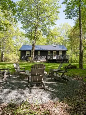 a cabin with picnic tables and chairs in front of it at Chic Cabin with Hot Tub and Fire Pit in Roscoe