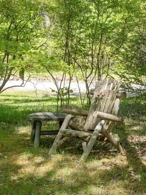a wooden bench sitting in the grass near trees at Chic Cabin with Hot Tub and Fire Pit in Roscoe