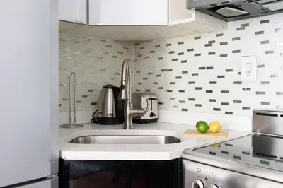 a white kitchen with a sink and a stove at 24-10 Studio in Prime Gramercy WD in Unit in New York