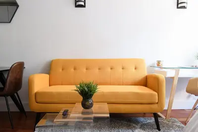 a yellow couch in a living room with a table at 24-10 Studio in Prime Gramercy WD in Unit in New York