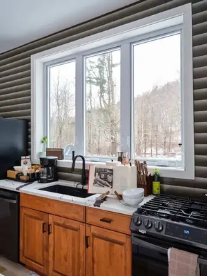 a kitchen with a sink and a stove and windows at Chic Renovated Chalet with Private Pond in Roscoe