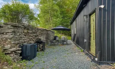 a stone wall next to a building with an umbrella at Chic Renovated Chalet with Private Pond in Roscoe