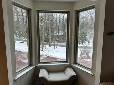 a window with a chair in a room with snow outside at Iron Hill in Lake Harmony