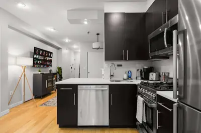 a kitchen with black cabinets and a stainless steel refrigerator at Beautiful Apartment in NYC in New York