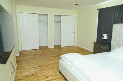 a bedroom with a white bed and four closets at Spacious 3 Bedroom, 15 Min to EWR Airport and Parks in Newark