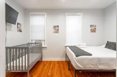 a bedroom with a crib and two windows at The Grand Retreat 9BR 4BA Near NYC and Airport in Bayonne
