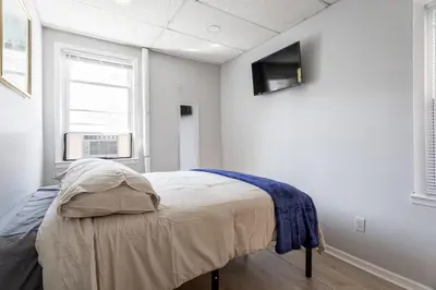 a bedroom with a bed and a tv on the wall at The Grand Retreat 9BR 4BA Near NYC and Airport in Bayonne