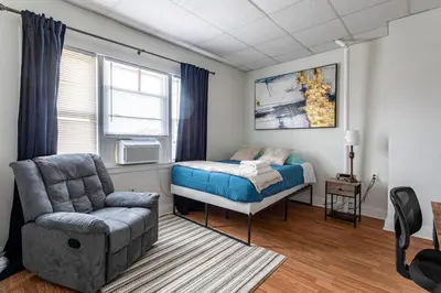 a bedroom with a bed and a chair at Deluxe 4BR 2BA Apartment Near NYC and Airport in Bayonne
