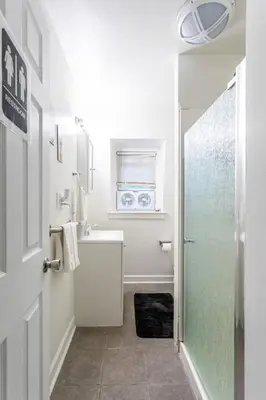 a white bathroom with a shower and a sink at Deluxe 4BR 2BA Apartment Near NYC and Airport in Bayonne