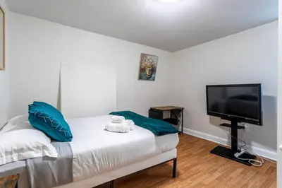 a bedroom with a bed and a flat screen tv at Deluxe 4BR 2BA Apartment Near NYC and Airport in Bayonne