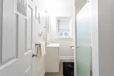 a white bathroom with a sink and a mirror at Deluxe 4BR 2BA Apartment Near NYC and Airport in Bayonne