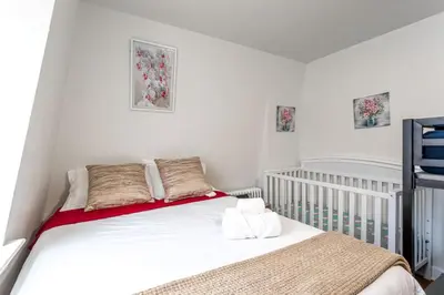 a small white bedroom with a crib and a bed at Deluxe 4BR 2BA Apartment Near NYC and Airport in Bayonne