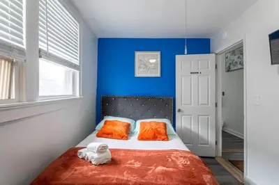 a bedroom with blue walls and a bed with orange pillows at Spacious 4BR 1BA Duplex Apartment Near NYC in Bayonne