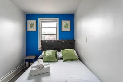 a bedroom with a bed with green pillows and a window at Spacious 4BR 1BA Duplex Apartment Near NYC in Bayonne