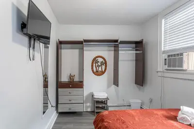 a bedroom with a bed and a dresser and a television at Spacious 4BR 1BA Duplex Apartment Near NYC in Bayonne