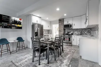 a kitchen with a table and chairs and a refrigerator at The Modern Retreat 4BR 2BA Near NYC and Airport in Bayonne
