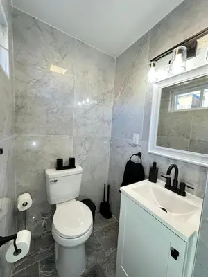 a bathroom with a white toilet and a sink at The Modern Retreat 4BR 2BA Near NYC and Airport in Bayonne