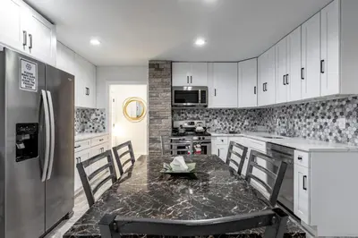 a kitchen with white cabinets and a stainless steel refrigerator at The Modern Retreat 4BR 2BA Near NYC and Airport in Bayonne